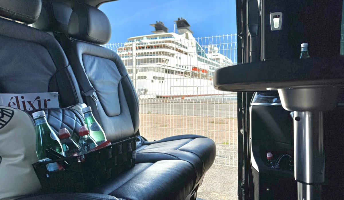 Intérieur d’un van haut de gamme DreamCarSud avec collations et eau minérale, stationné devant un terminal croisière, prêt pour un transfert privé au départ du port de Sète ou Marseille